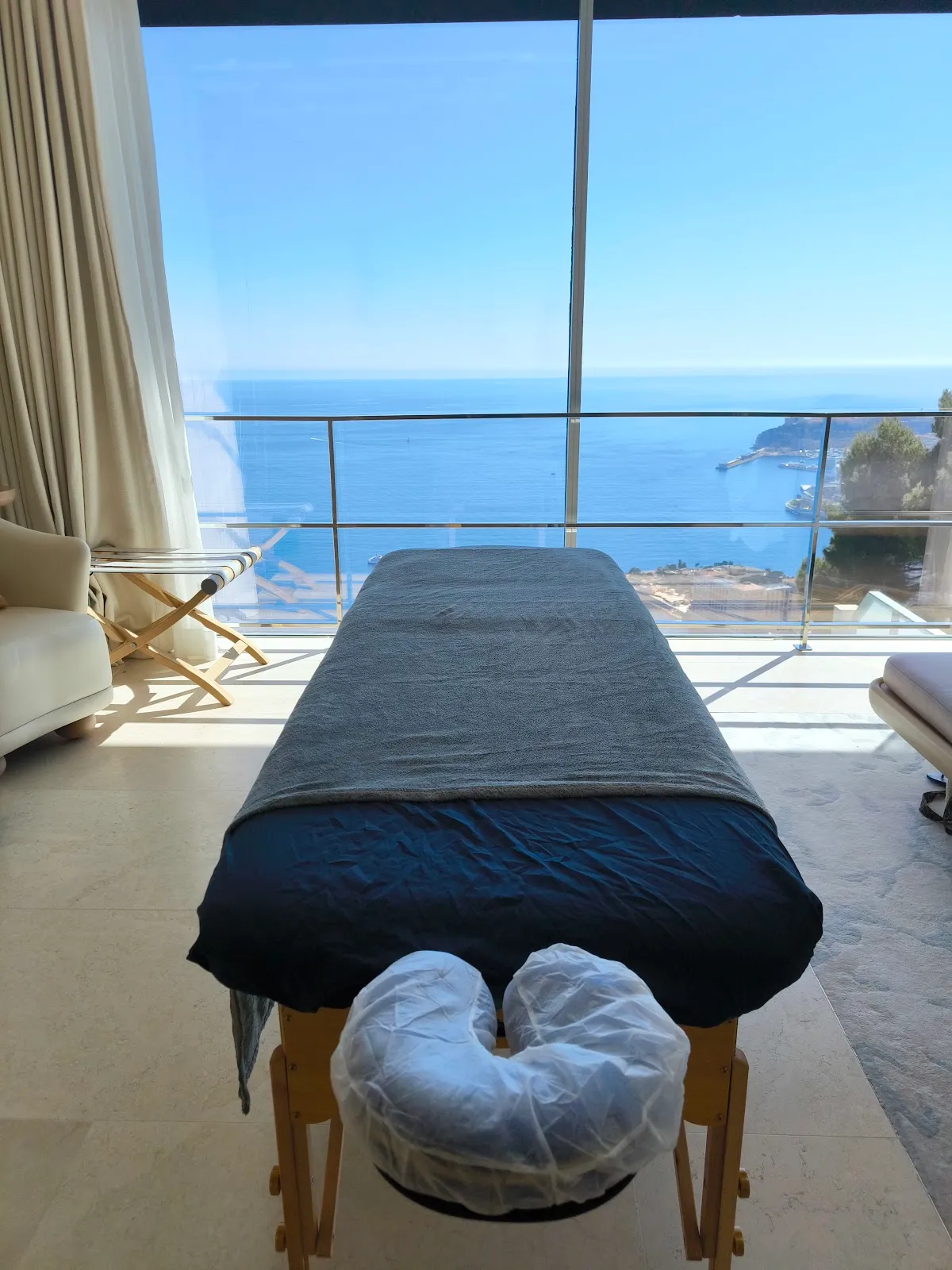 Massage table set up by a bay window, overlooking the sea and Monaco
